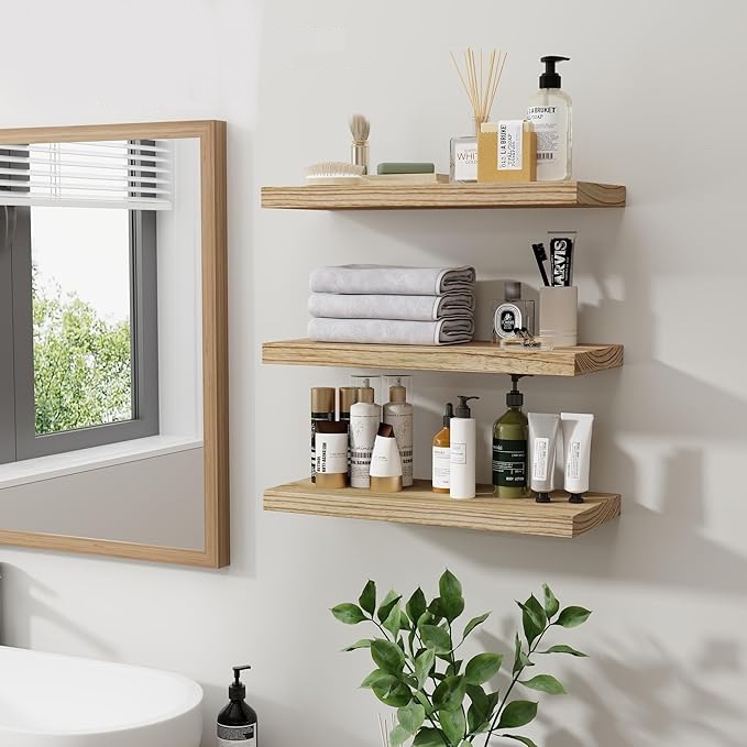 8 Simple DIY Home Projects For Beginners - Wooden floating shelves in a bathroom holding toiletries, towels, and decor items for an organized, minimalist look