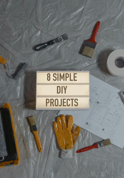 8 Simple DIY Home Projects For Beginners - Top view of essential tools for 8 simple DIY projects, including paintbrushes, roller, gloves, paint swatches, and blueprint layout on a plastic-covered surface